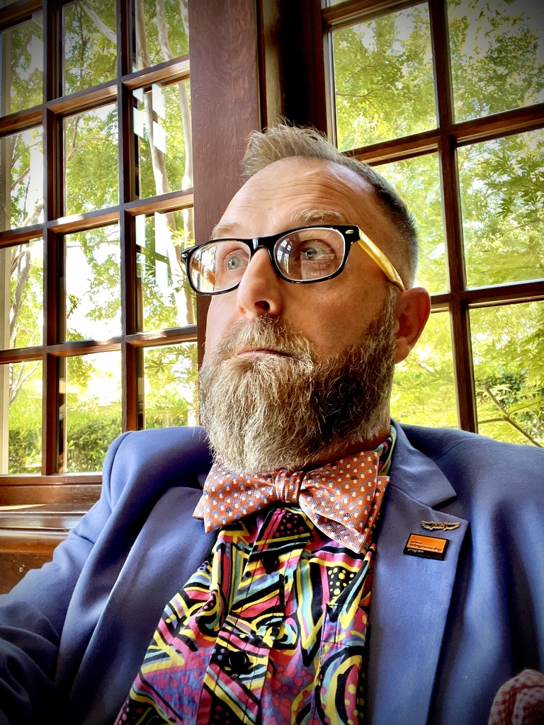 Brandon Green - Founder of The Lone Star Local, wearing blue suit with orange bow tie and colorful shirt